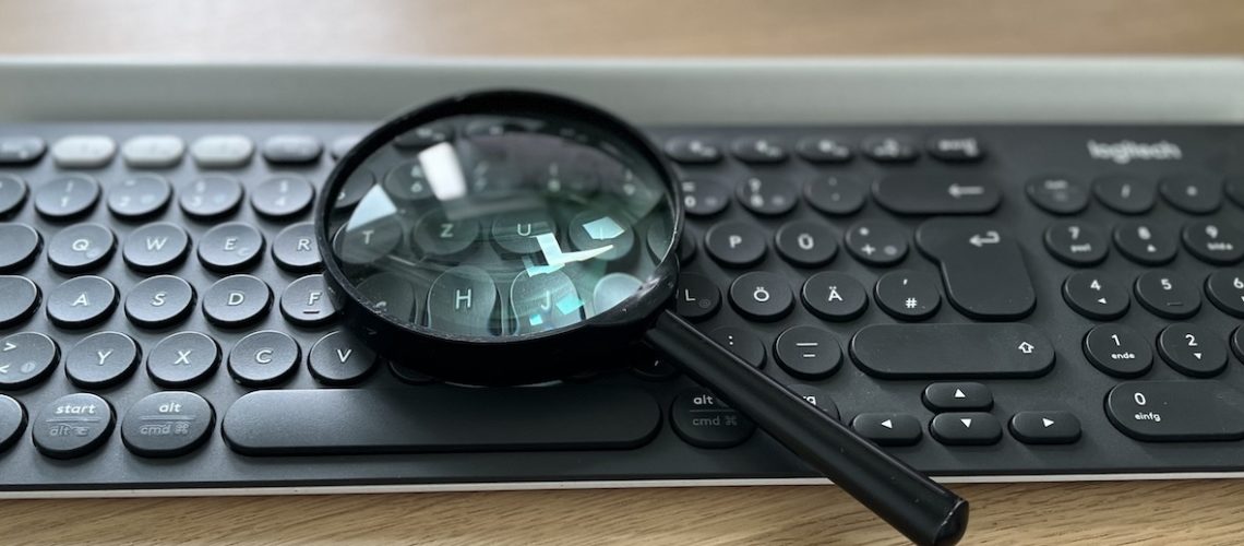 Tastatur auf der eine Lupe liegt - soll die Suchintention verdeutlichen
